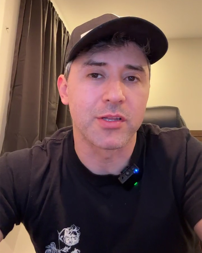 MAGA influencer speaking in a black shirt and cap, discussing his detention by ICE related to deportation claims.