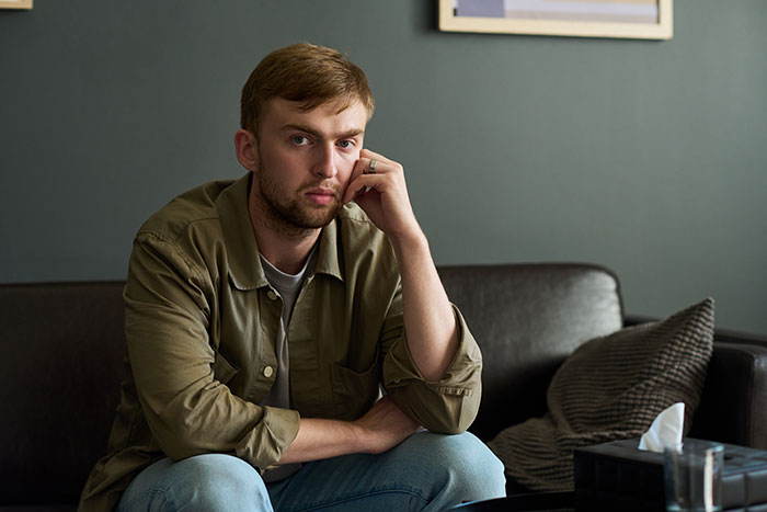 Man sitting on a couch looking thoughtful, reflecting on challenges of dating as a single mom drama.