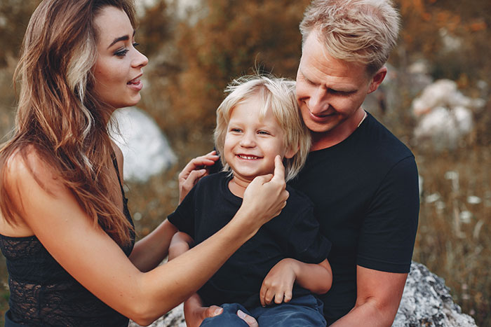 Man dating single mom spending time outdoors with her child and smiling during a family moment in nature.