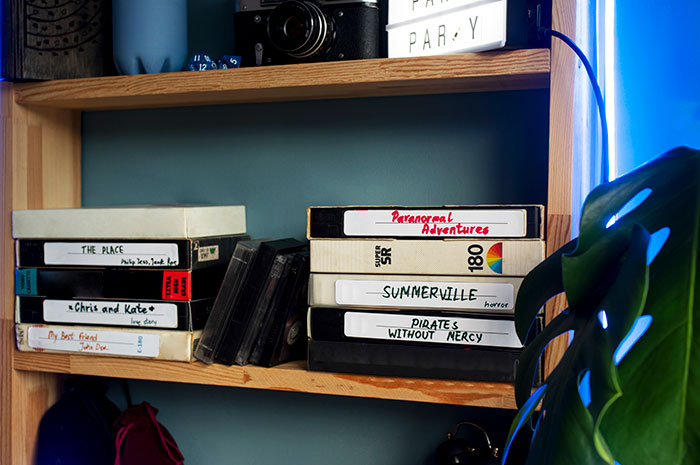 Stack of vintage VHS tapes on a wooden shelf, highlighting themes of free labor and volunteer refusal in relationship dynamics.