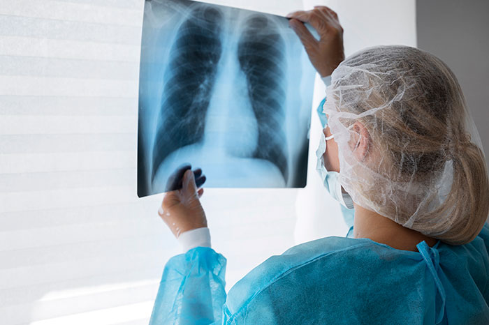 Medical professional examining a chest X-ray highlighting concerns of medical misogyny affecting women’s health care risks.