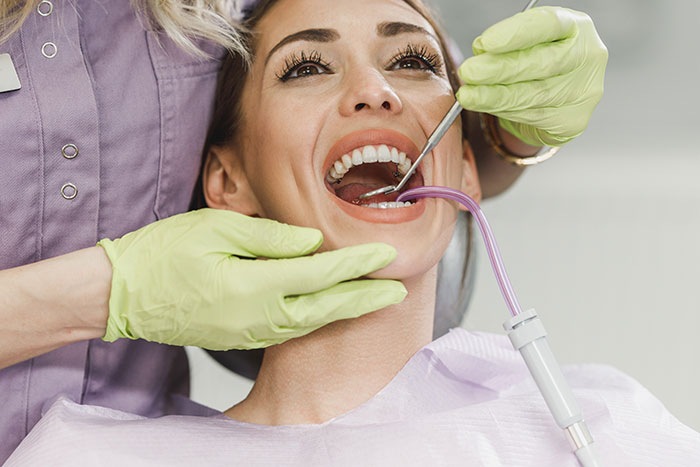 Woman receiving dental exam from healthcare professional wearing gloves, highlighting medical misogyny and women’s health risks.