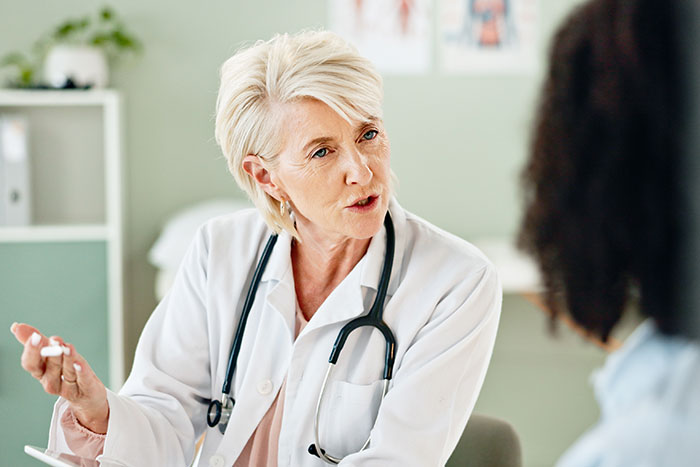 Female doctor in a white coat discussing women’s health risks, highlighting medical misogyny and patient safety concerns.
