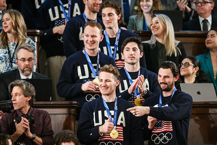 US women's hockey players wearing gold medals and USA sweaters at a public event, reacting to a distasteful joke.