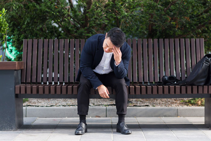Young man dressed in black sitting alone on a bench looking regretful after meeting a woman he met online. Young man dressed in black sitting alone on a bench looking regretful after meeting a woman he met online.
