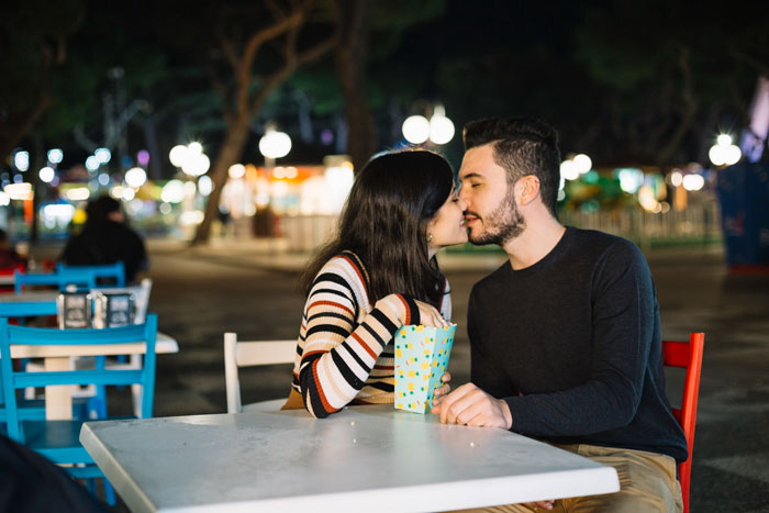 Couple sharing a close moment at an outdoor table during a date after meeting online and traveling long distance. Couple sharing a close moment at an outdoor table during a date after meeting online and traveling long distance.
