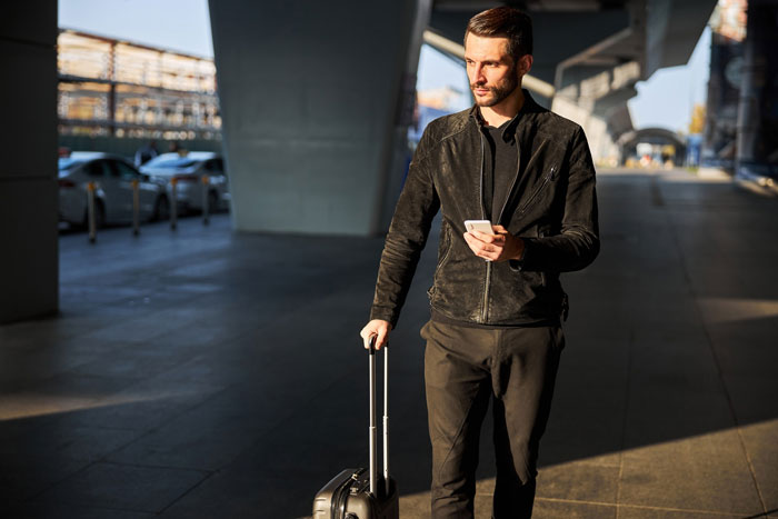 Man traveling with suitcase and phone, representing 29YO traveling 7000km to meet woman he met online. Man traveling with suitcase and phone, representing 29YO traveling 7000km to meet woman he met online.