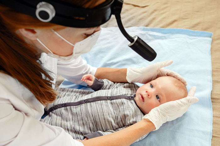 Doctor wearing gloves and mask examining a newborn baby, highlighting concerns faced by new parents with CPS involvement. Doctor wearing gloves and mask examining a newborn baby, highlighting concerns faced by new parents with CPS involvement.
