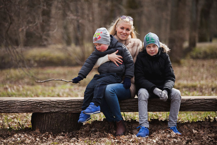 Mother with two sons sitting on a bench outdoors, symbolizing a couple in shock after religious MIL kidnaps their son. Mother with two sons sitting on a bench outdoors, symbolizing a couple in shock after religious MIL kidnaps their son.