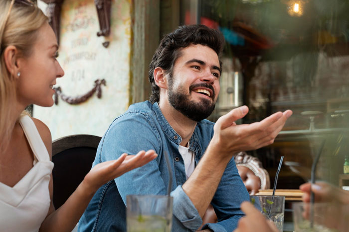 Young man accused by mother-in-law of changing after cutting toxic family ties, smiling and talking at a social gathering.