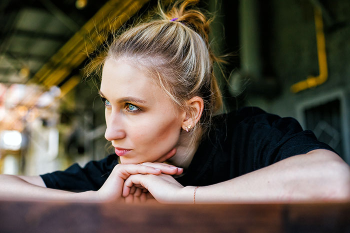 Young woman with blonde hair resting chin on hands, looking thoughtful in an indoor setting about meds and child safety.