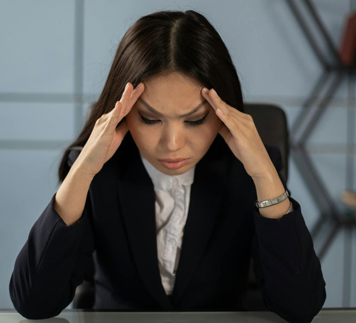 Stressed nurse holding temples, worried about secret date and HIPAA privacy concerns in an office setting.
