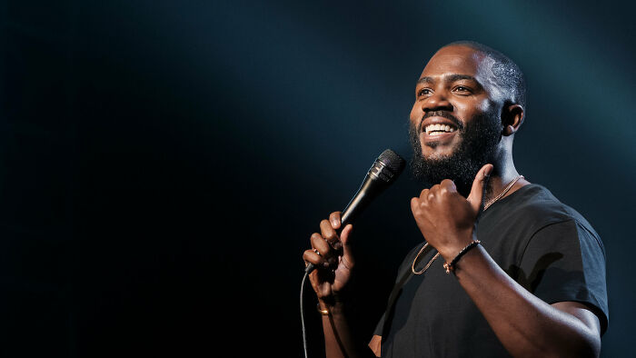 Comedian performing with a microphone on stage, highlighting what to watch on Netflix this weekend latest releases.