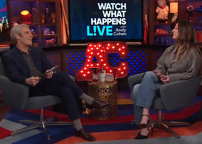 Talk show host interviewing guest amid set decorations, featuring lit initials AG, discussing toxic mom and celebrity drama.