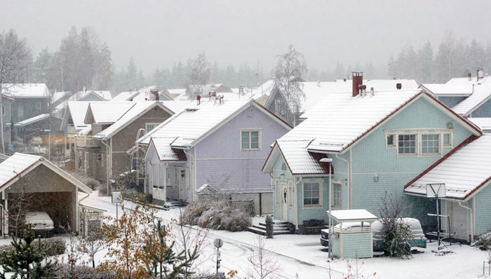 Snow-covered houses in a neighborhood during a snowstorm showing temperatures rise and winter weather conditions.