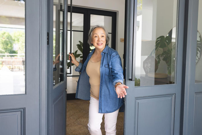 Middle-aged woman opening door during snowstorm refusing to house neighbor and their dog, tensions rise amid cold temperatures.