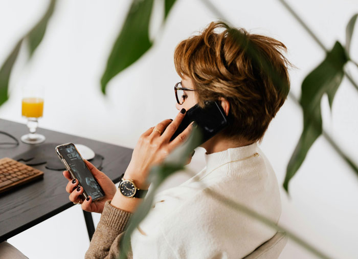 Teen talking on phone and holding smartphone, illustrating story of teen becoming an exemplary son after mom&rsquo;s punishment.