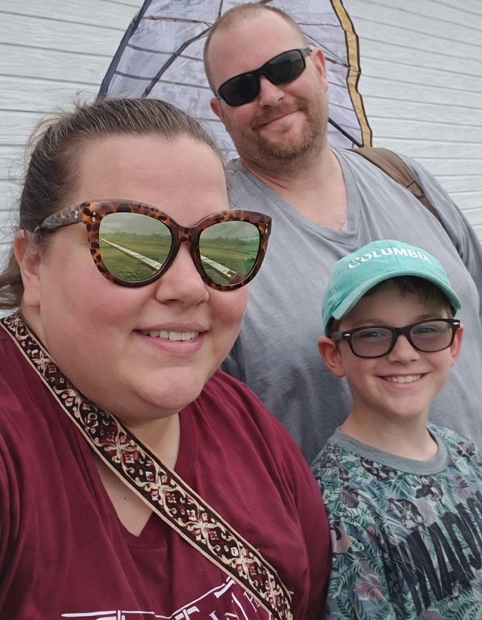 Heartbroken mom of 11-year-old with adoptive father slain, posing outdoors with man and boy smiling together.