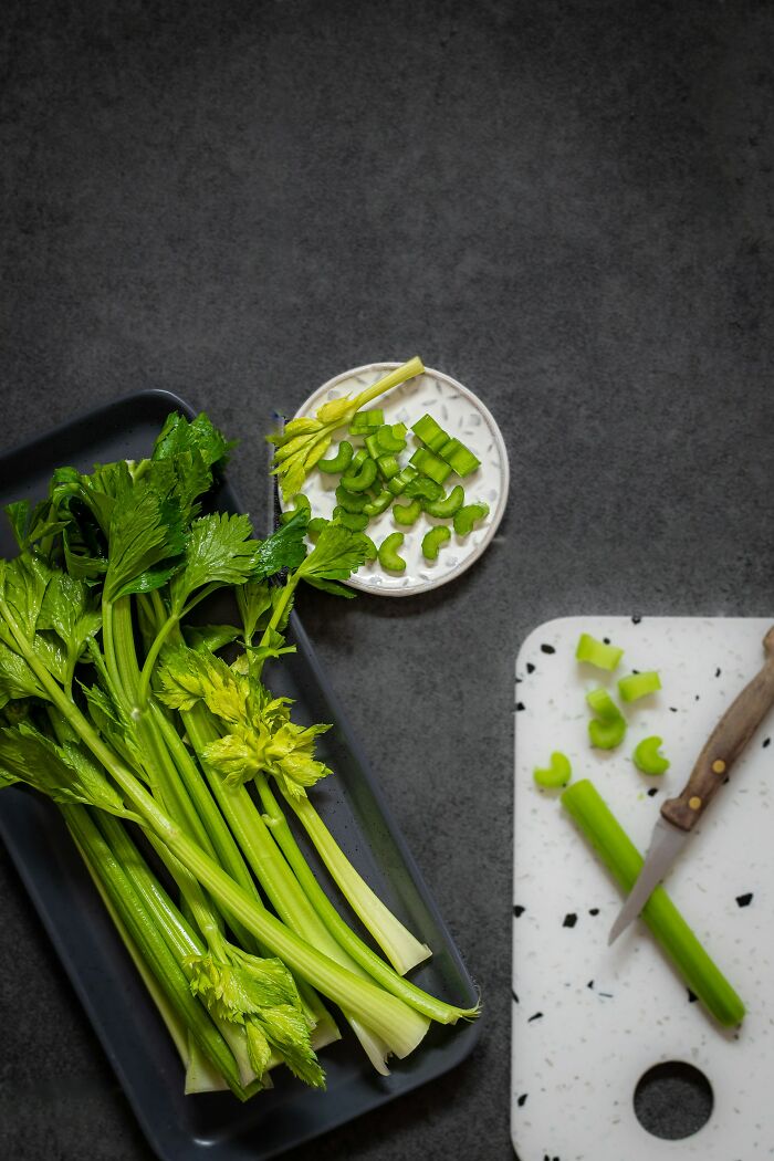 Fresh celery stalks and sliced pieces on a tray and cutting board, illustrating conversation starter facts about celery.