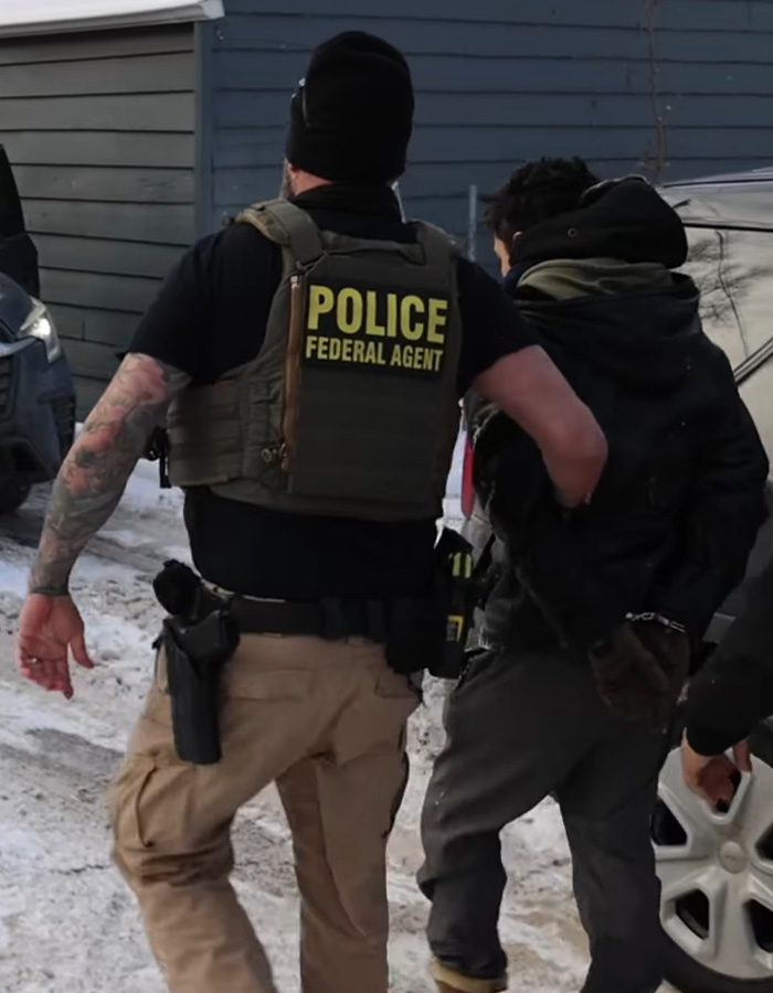 Federal agent escorting a handcuffed individual outdoors, highlighting felonies and law enforcement action.