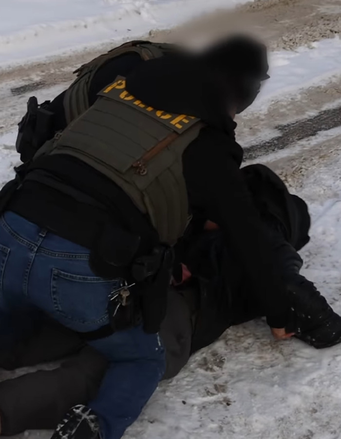 Police officer detaining a suspect on a snowy ground, illustrating felonies connected to Trump in recent news.