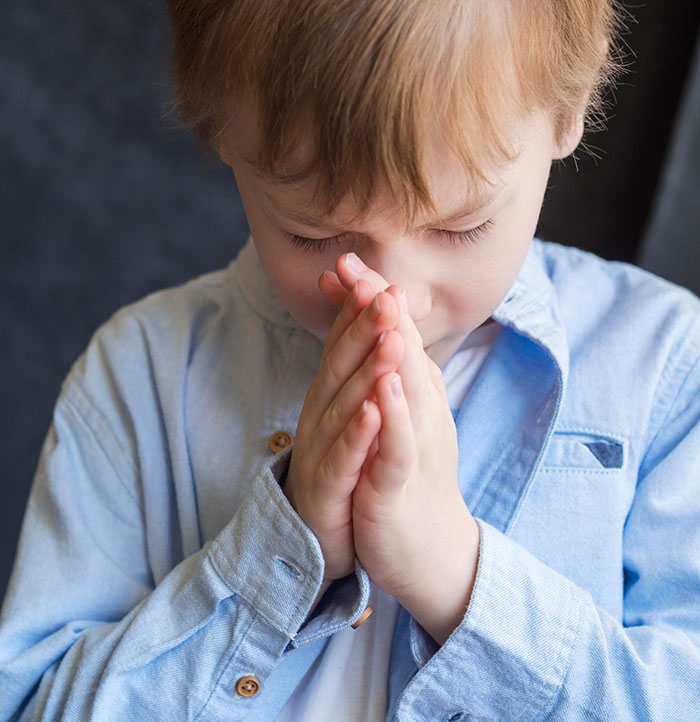 Young student softly praying with eyes closed, reflecting the emotional moments teachers face when students confide disturbing things.