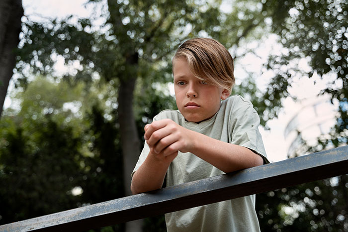 Sad young student looking down outdoors, reflecting the disturbing things students confided in teachers.