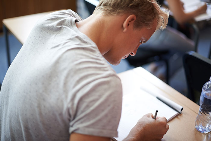 Student writing in a classroom, representing teachers and the most disturbing things students confided in them.