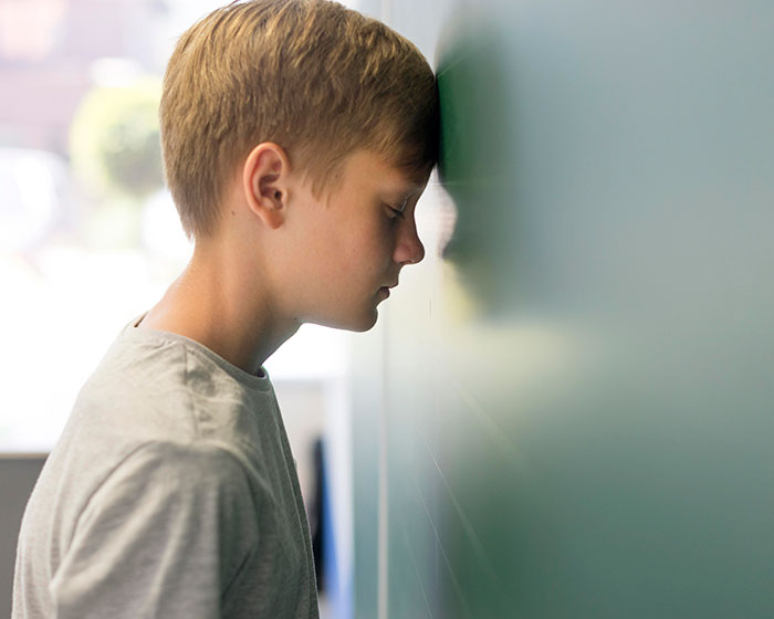 Young student leaning forehead against wall, illustrating the disturbing things students confided in teachers.