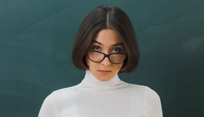 Female teacher wearing glasses and white turtleneck standing in front of chalkboard about disturbing things students confided in them