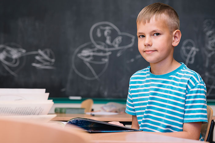 Young student sitting in classroom with book, representing teachers sharing the most disturbing things students confided in them