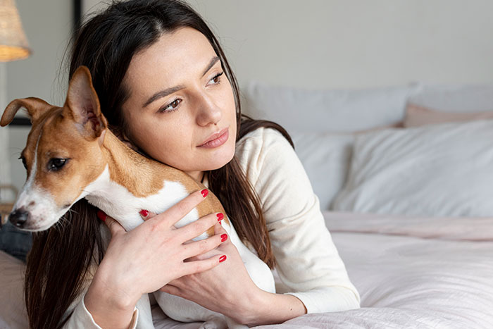 Young woman hugging a dog on a bed, reflecting comfort and trust in a calm home setting, related to disturbing student confessions.