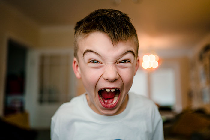 Young boy yelling intensely indoors, illustrating emotions related to teachers and disturbing student confessions.