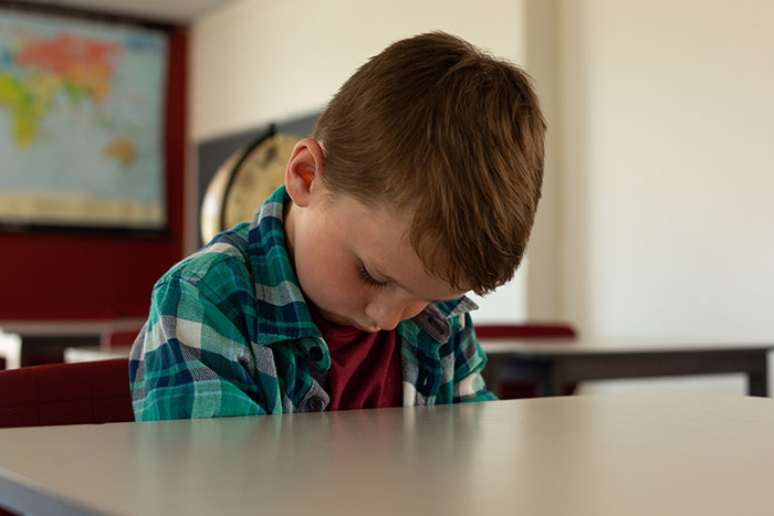 Young boy in classroom looking down, reflecting the disturbing things students confided in teachers during school hours.