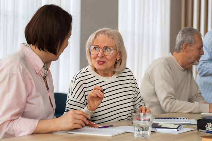 Older woman speaking to younger woman at a table, representing granny pretending to be kid's guardian in family setting.