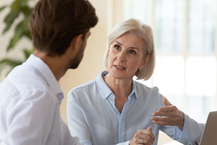 Elderly woman speaking seriously to a younger man, depicting granny pretending to be kid's guardian.