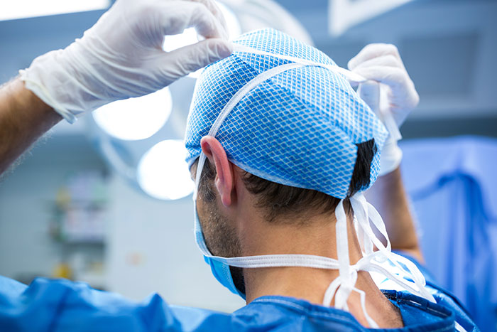 Surgeon adjusting cap in operating room preparing for procedure related to throat pain medical mystery.