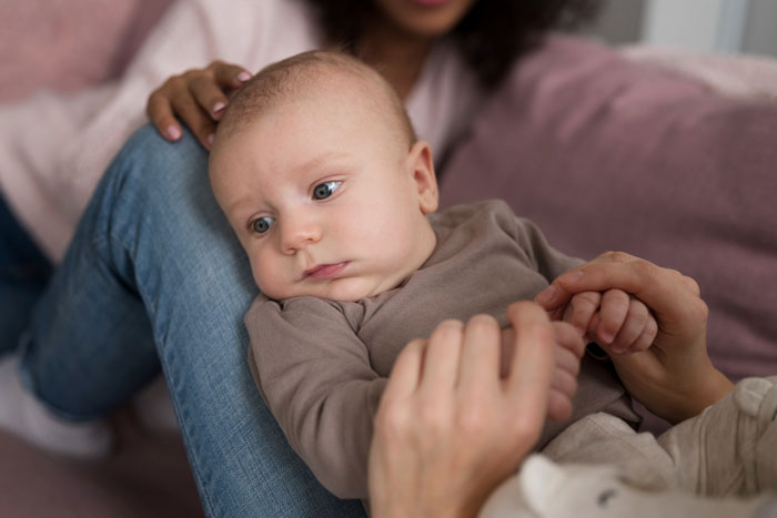 Baby boy resting on a parent&rsquo;s lap while holding hands, illustrating concepts of naming son Harry Potter.
