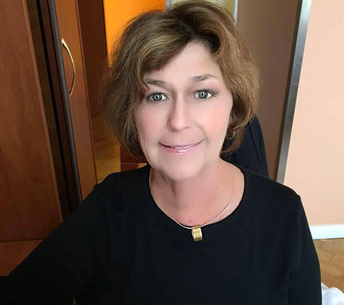 Middle-aged woman indoors, smiling gently, representing former CIA member theory on disappearance of Savannah Guthrie's mom.