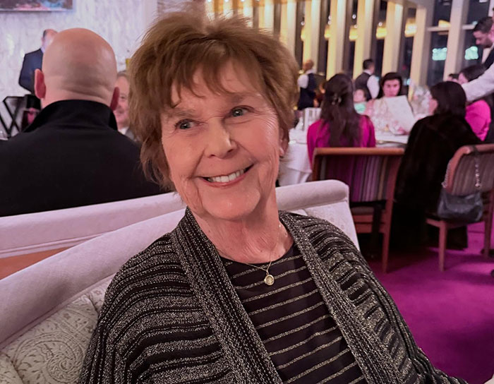 Elderly woman smiling warmly at a restaurant, related to former CIA member theory on Savannah Guthrie's mom disappearance.