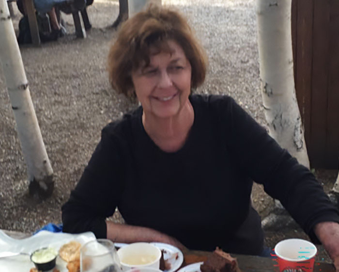 Woman sitting at outdoor table with food and drinks during search for Savannah Guthrie's mom updates after expired deadline