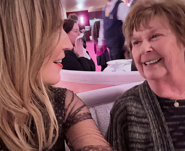 Two women smiling and conversing in a cozy setting, relating to a man detained in connection with kidnapping.