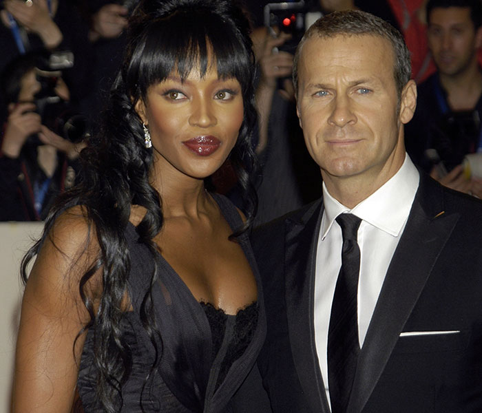 Naomi Campbell attending an event in a black dress alongside a man in a black suit, Epstein files reveal involving Ghislaine Maxwell.