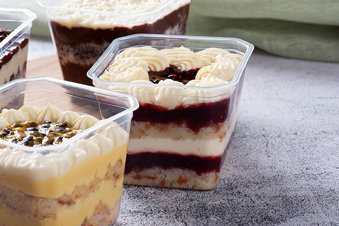 Assorted creamy layered desserts in clear containers, highlighting the concept of pay deserts in neighbor dog walking services.