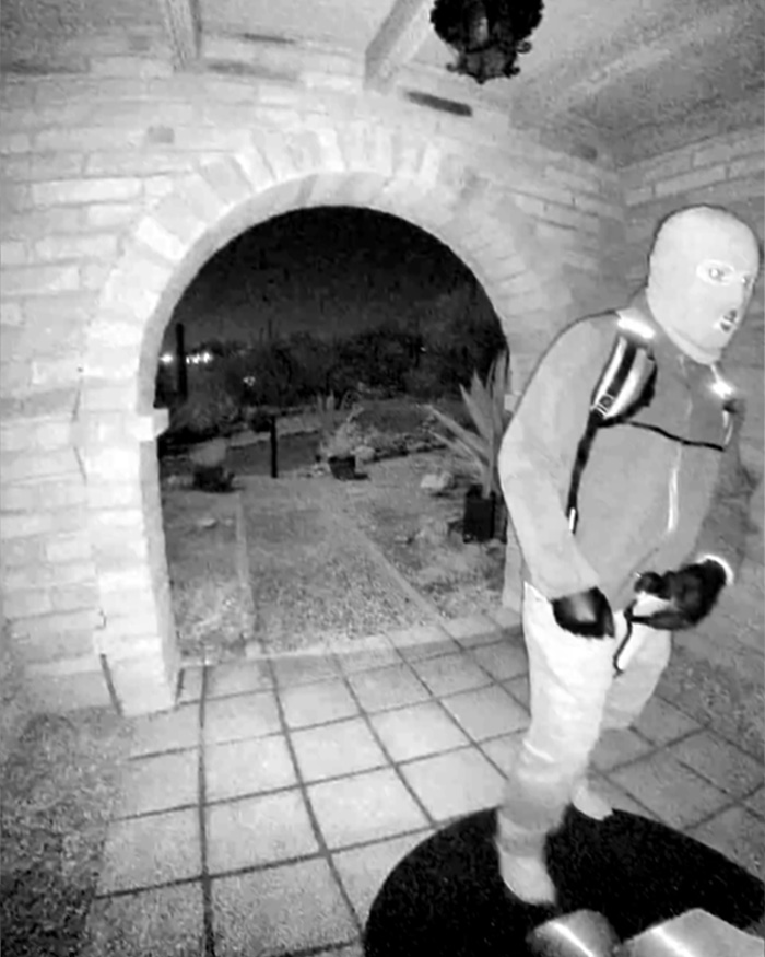 Suspect in Nancy Guthrie case captured on doorbell camera at night wearing mask and gloves near front entrance.