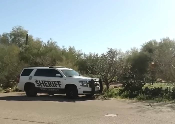 Police sheriff vehicle parked on a sunny road near trees during an investigation of bitcoin ransom note demand.