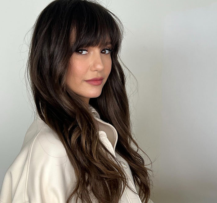Woman with long dark hair and bangs wearing a white jacket, representing Eric Dane’s stunning first symptom of ALS diagnosis.