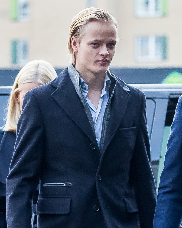 Son of Norway's Crown Princess arriving at court, wearing a dark coat and displaying a serious expression.