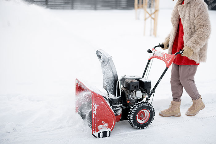 Woman using a new snow blower outdoors in winter, refusing to lend it to a neighbor she never met before.