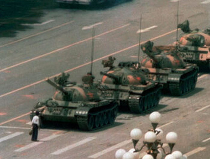 Man standing alone in front of a line of military tanks on a city street, a powerful photo from around the world.